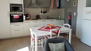 Une cuisine de taille réduite avec des meubles blancs, un four à micro-ondes, une cuisinière et un évier.