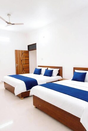 A hotel room with two beds, wooden headboards, white bedding, and a ceiling fan. - Hotel Shri Geeta Dham Near Prem Mandir (Mathura)