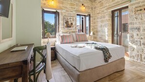 Ein Schlafzimmer mit Steinsturz, einem Bett mit gestreiften Kissen, einem Schreibtisch mit Laptop und einem Fenster mit Blick.