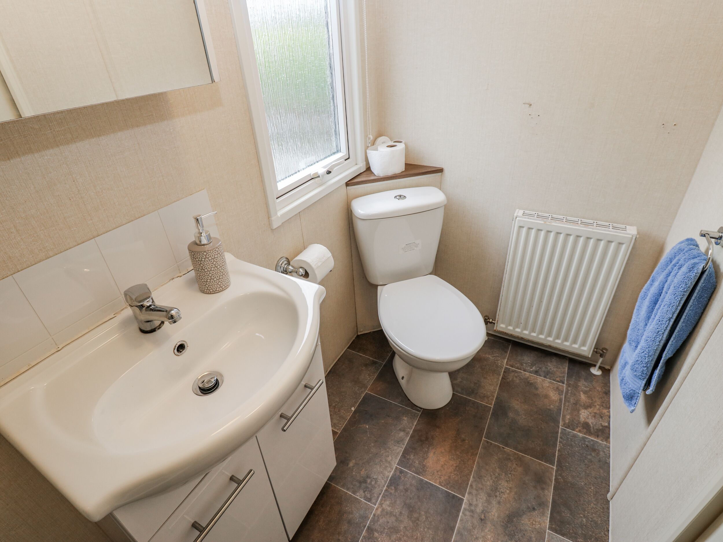 Een badkamer met een wastafel, toilet en raam.
