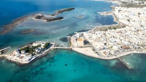 An aerial view of a coastal town with a marina, clear blue waters, and white buildings. - Villa Solaria - Giardino Privato and Aria Condizionata (Porto Cesareo)