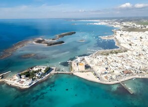 An aerial view of a coastal town with a marina, clear blue waters, and white buildings. - Villa Solaria - Giardino Privato and Aria Condizionata (Porto Cesareo)