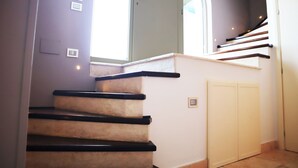 Una escalera con barandas negras y peldaños color beige que conduce a una plataforma.