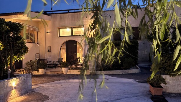 Un edificio moderno con patio, mobiliario exterior y plantas en macetas.