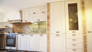 Una cocina con armarios blancos, estufa y salpicadero de azulejos.