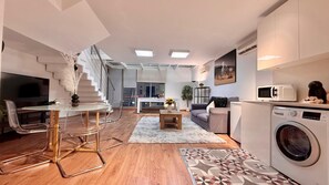 Un appartamento moderno con zona pranzo, soggiorno, cucina e una scala che conduce a un piano superiore.