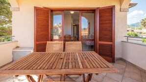 Een houten tafel met stoelen op een balkon, met uitzicht op de omgeving.