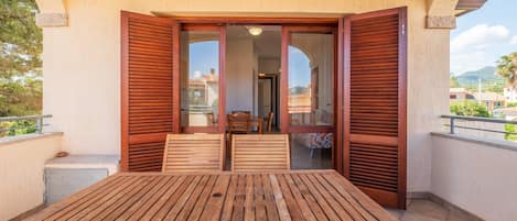 A wooden table and chairs on a balcony with a view of the surrounding area.