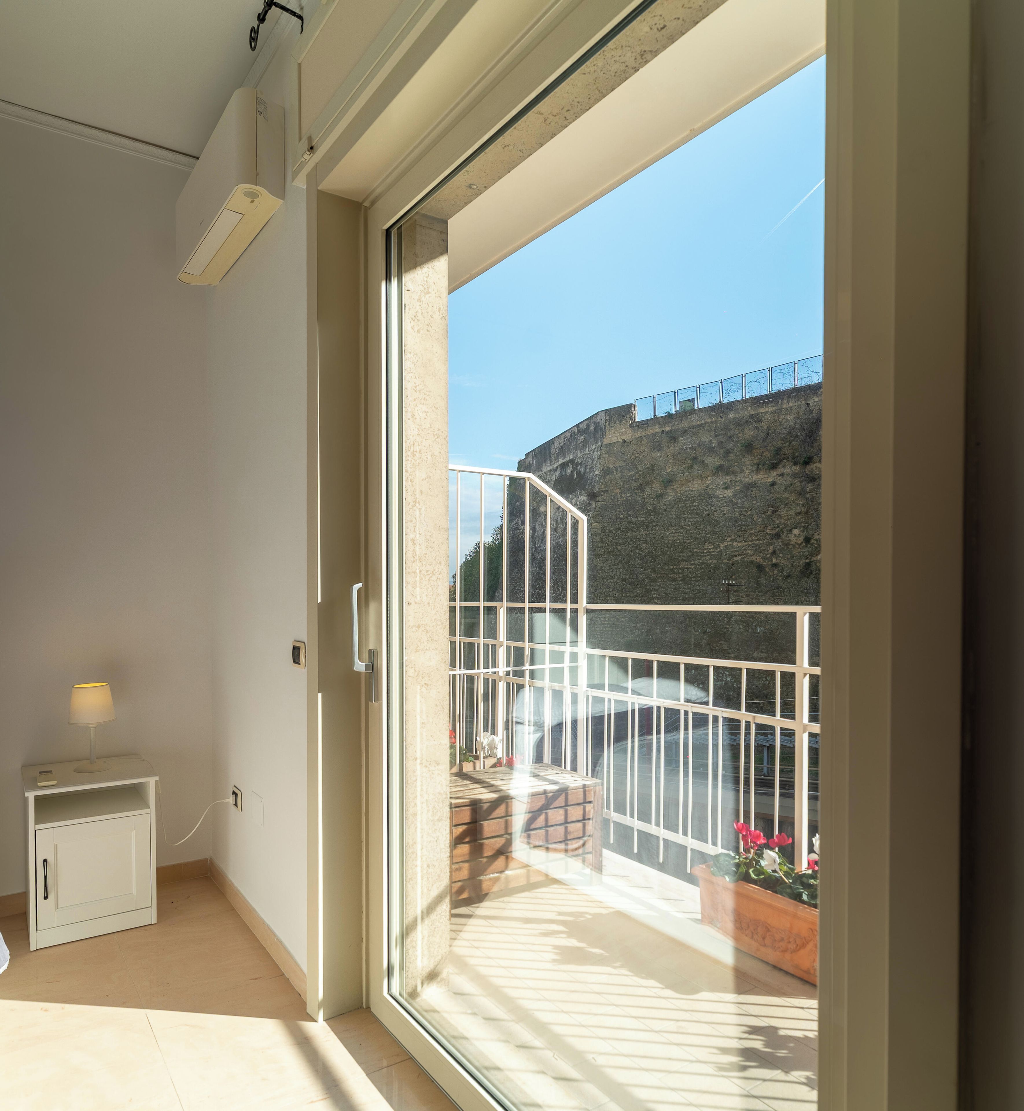 Une pièce dotée d’une porte-fenêtre coulissante qui donne sur un balcon avec une rambarde en métal et d’où l’on peut admirer un immeuble.
