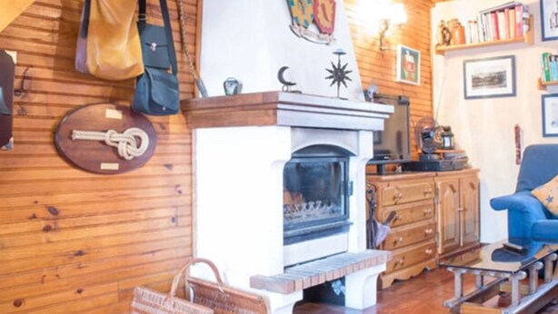 A cozy room with wooden walls, a fireplace, a blue armchair, and a woven basket. - Chalet at 50 meters from the ski slopes "Les Angles (Les Angles)