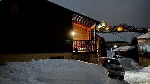 A snow-covered landscape with a building featuring a lit porch and a car parked in front. - Chalet at 50 meters from the ski slopes "Les Angles (Les Angles)