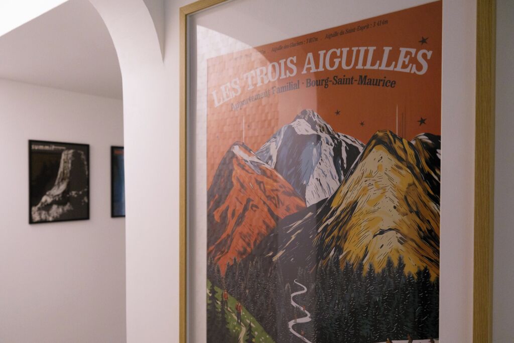 A framed poster of 'Les Trois Aiguilles' with a mountain landscape.