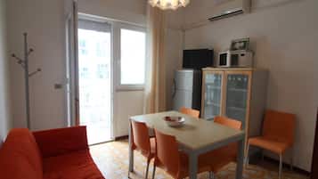 A compact living space with a dining area, a sofa, and a kitchenette.