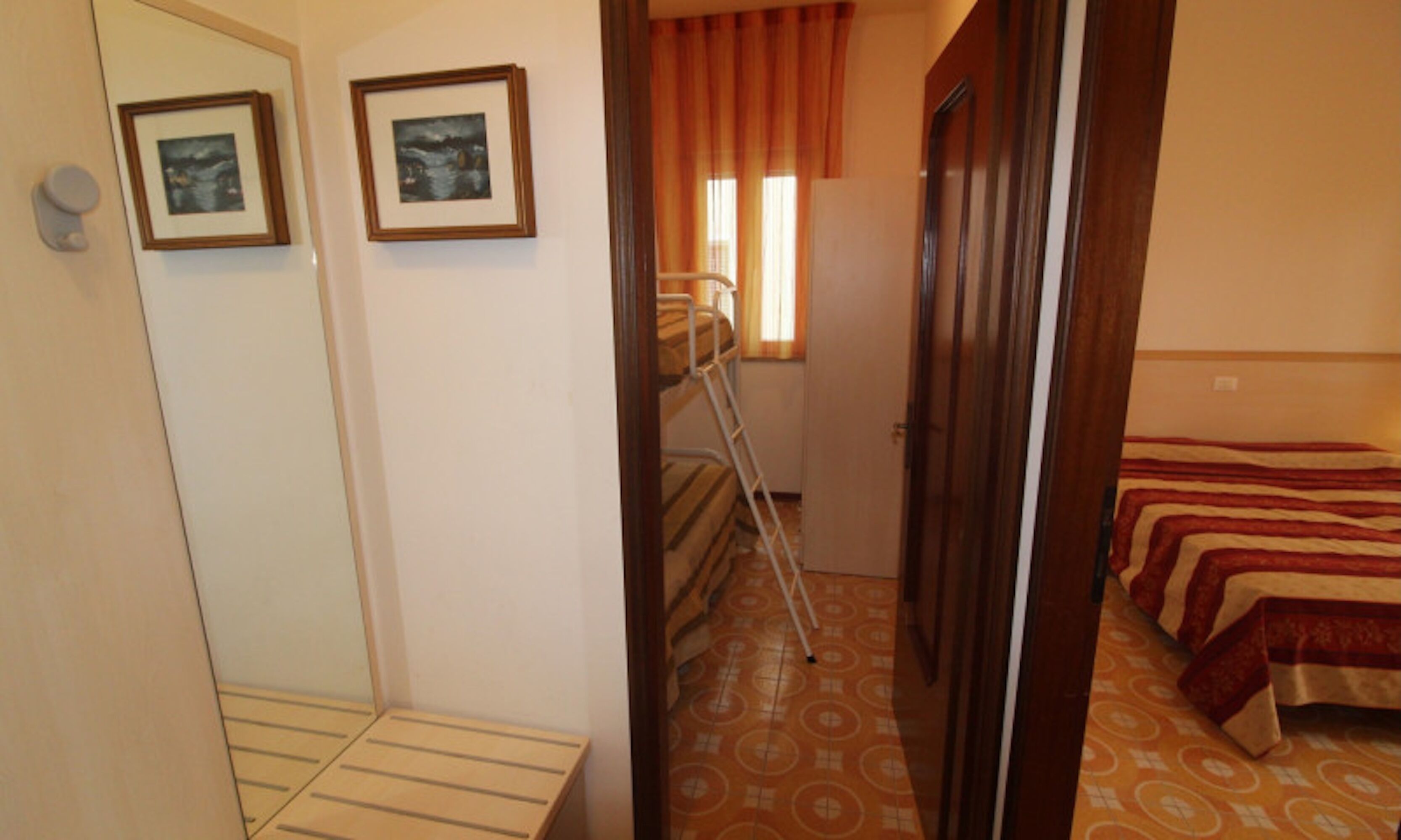 A room with bunk beds, a ladder, and two framed pictures on the wall.
