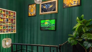 A staircase with a green wall adorned with framed artwork, including a tiger and abstract pieces. - Residenza Ricasoli (Grosseto)