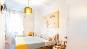 Un dormitorio con cama, mesitas de noche, una lámpara colgante, un mapa en la pared y una ventana con cortinas.