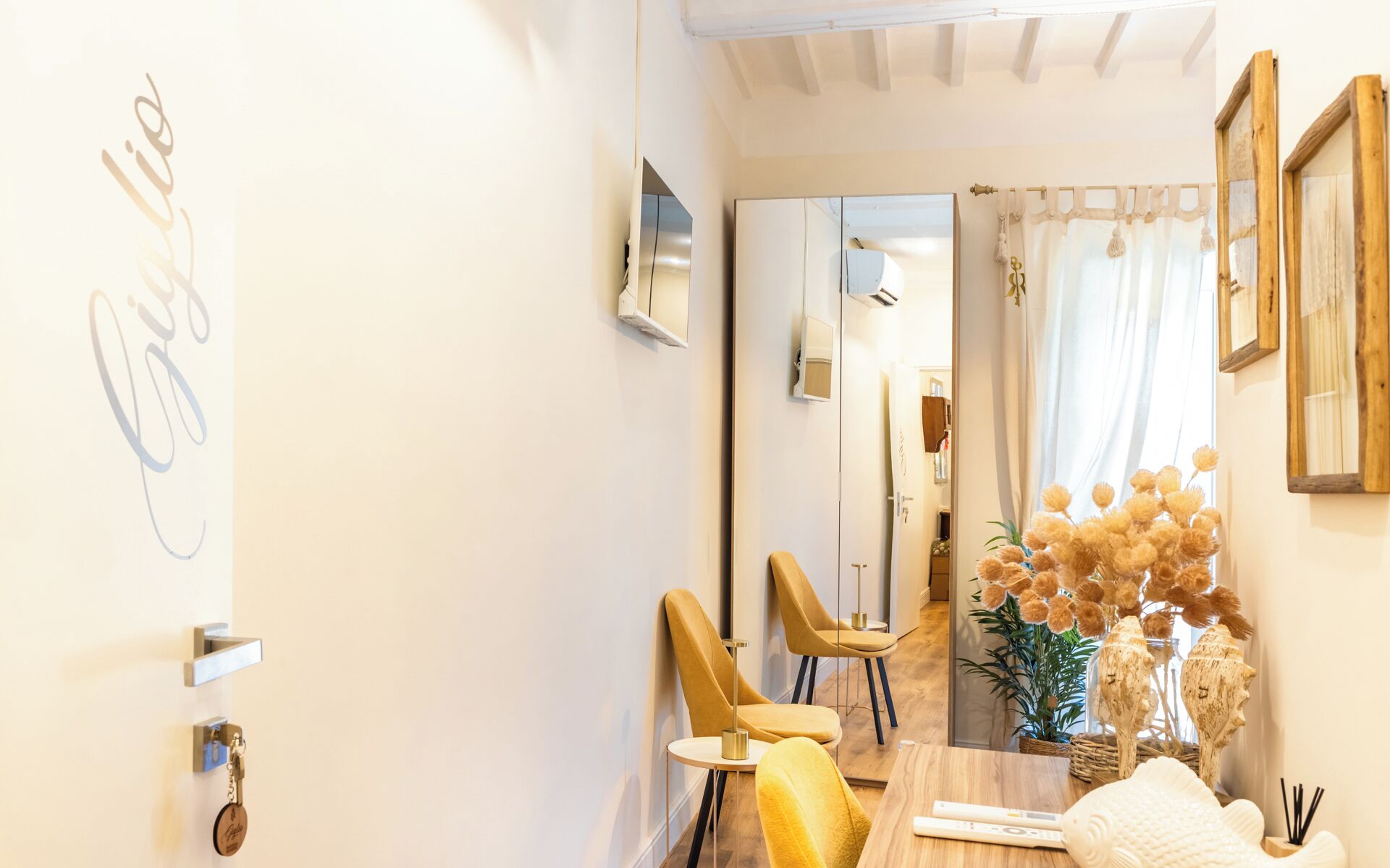Habitación de hotel moderna con diseño minimalista, suelo de madera, una pequeña mesa redonda, un sillón cómodo y un espejo grande.