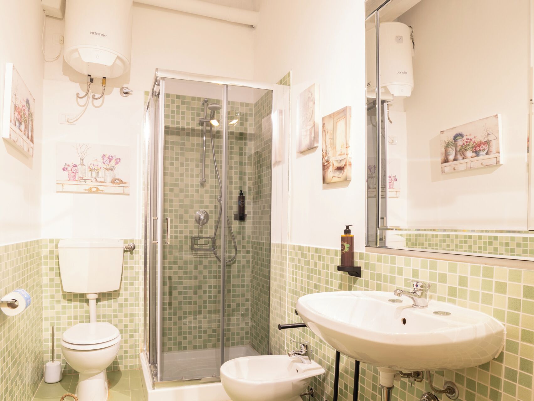 A bathroom with a shower, toilet, sink, and a mirror.