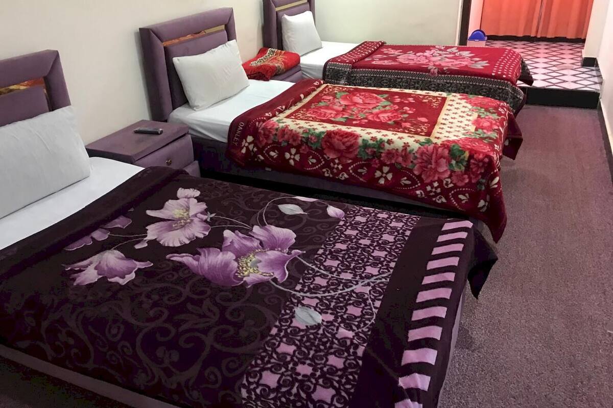 A hotel room with three beds, each with a different floral bedspread.