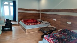 Une chambre avec deux lits, une petite table et une fenêtre.