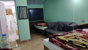 Une pièce comprenant un lit, un canapé, un téléviseur et une salle de bain visible à travers une porte ouverte.