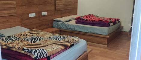 A bedroom with two beds, wooden headboards, and a light-colored floor.