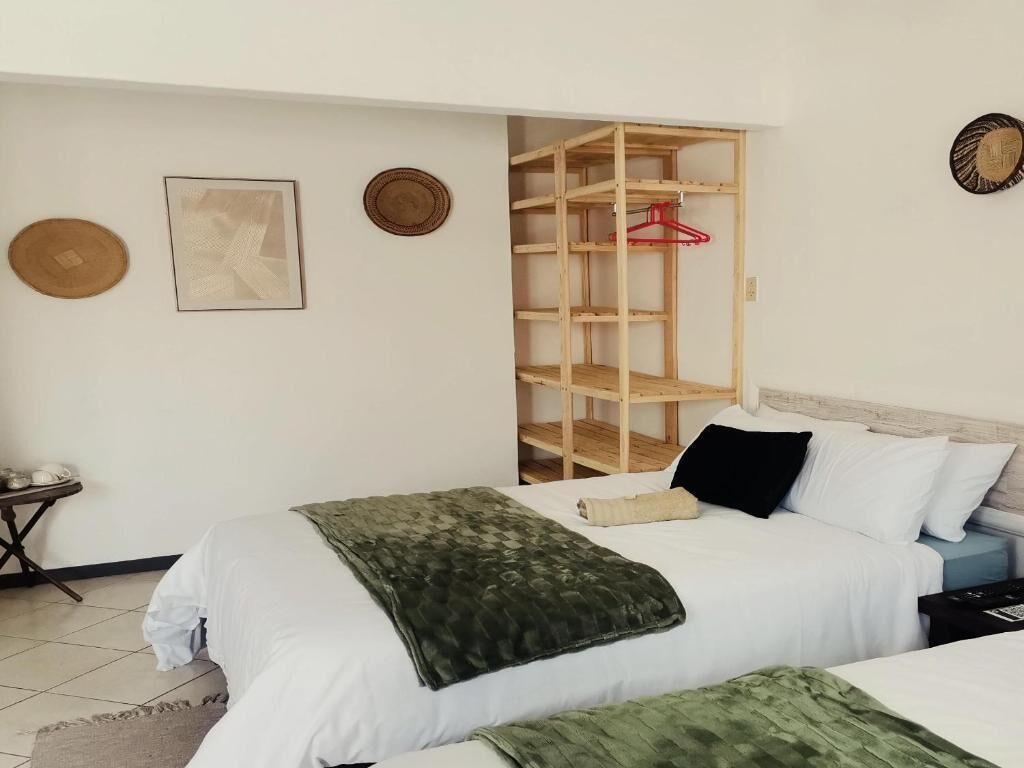 A bedroom with two beds, a wooden wardrobe, and a small table with a basket.