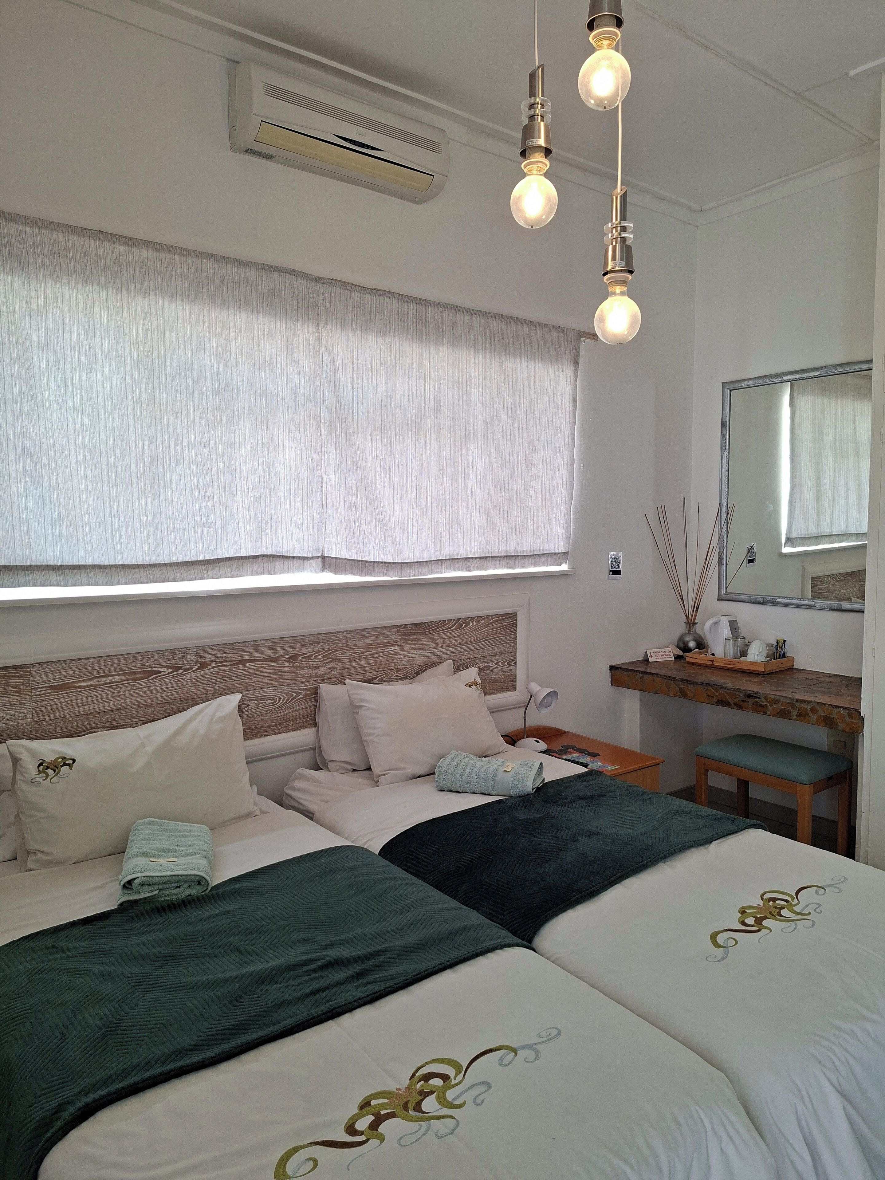 A neatly arranged bedroom with a large bed, a bedside table, a mirror, and a window with curtains.