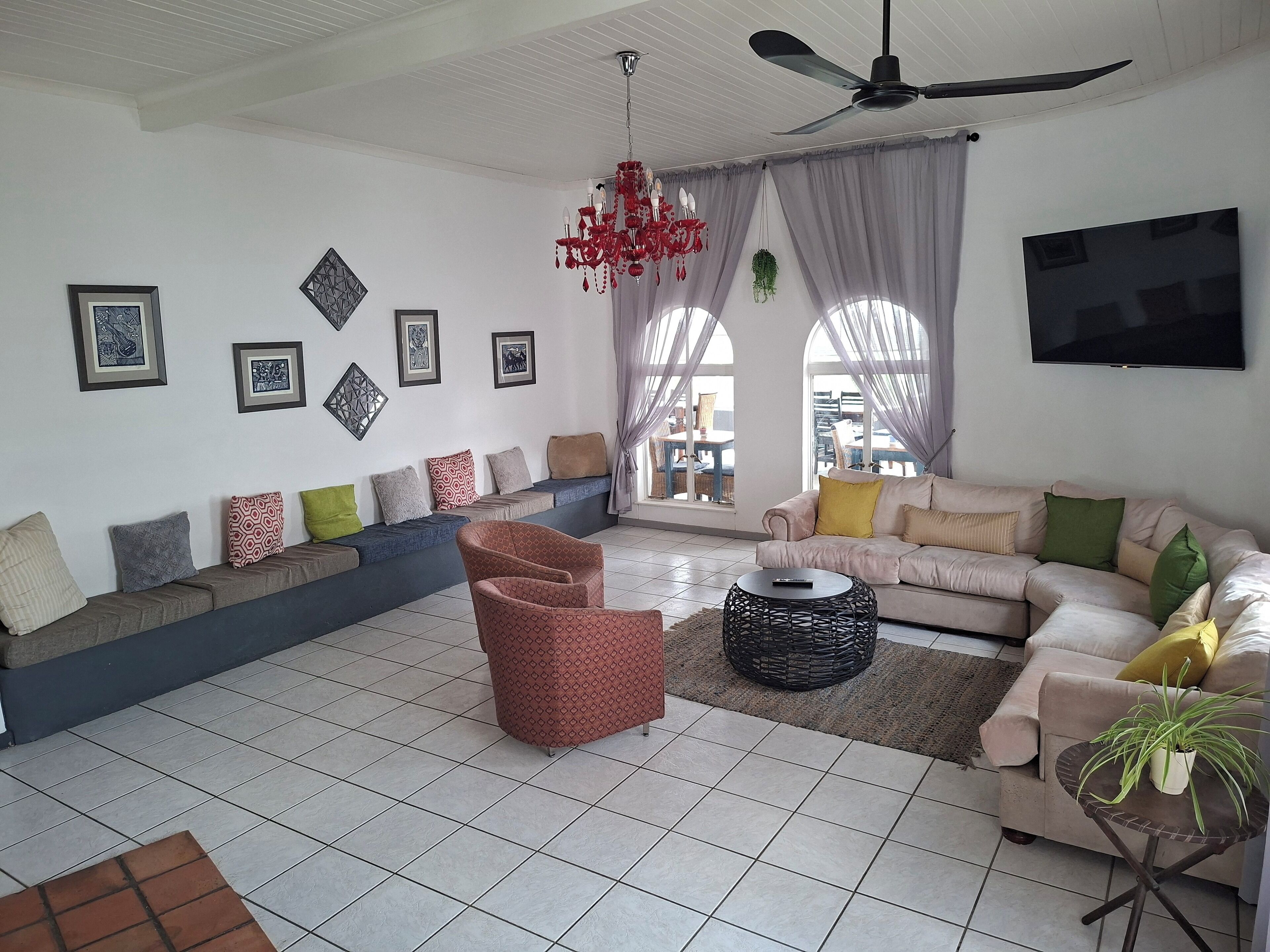 A living room with a sofa set, a red armchair, a round coffee table, and a TV mounted on the wall.