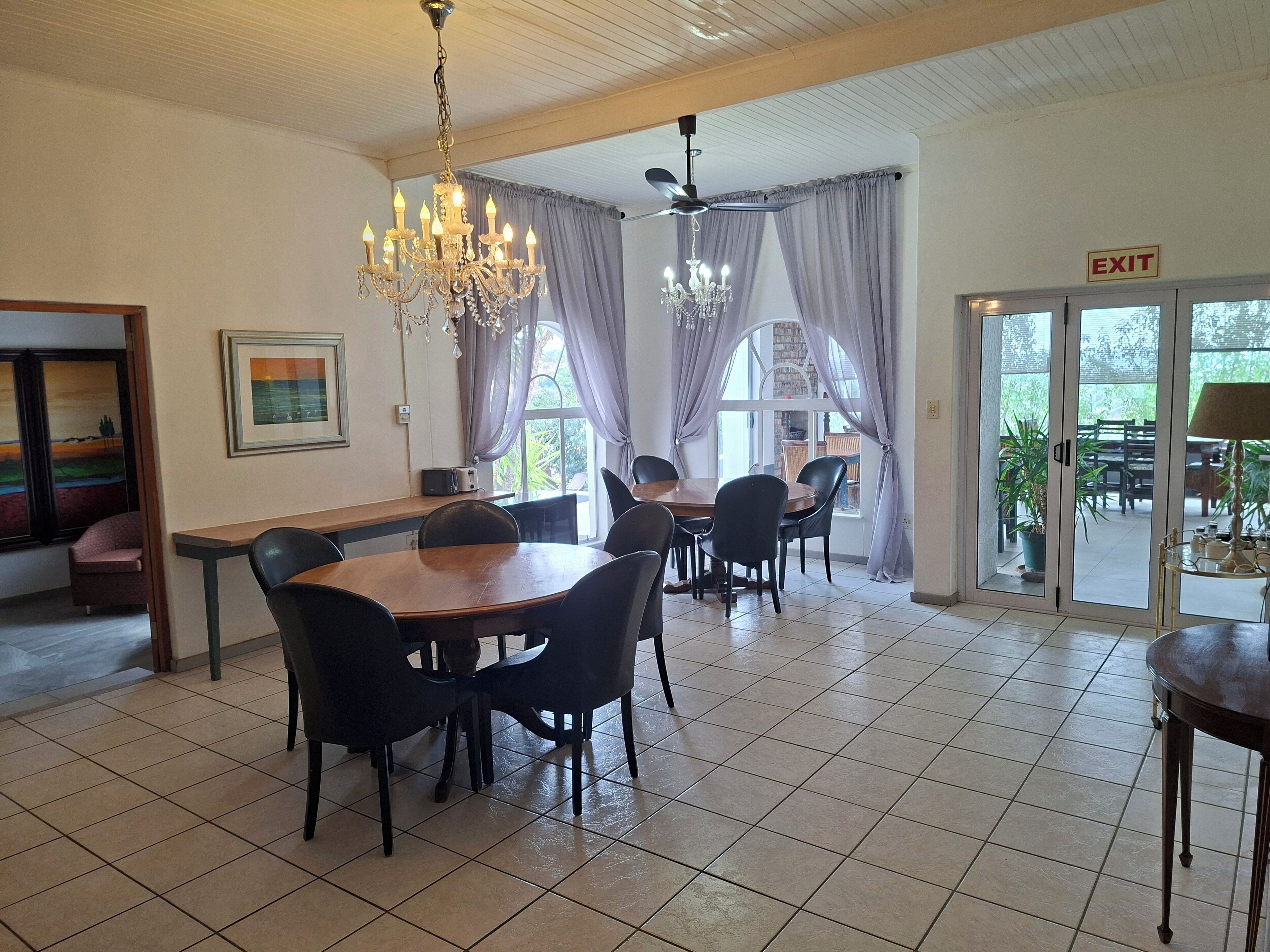 Un espace repas agrémenté d’un lustre, d’une table avec des chaises et d’un panneau indiquant la sortie.
