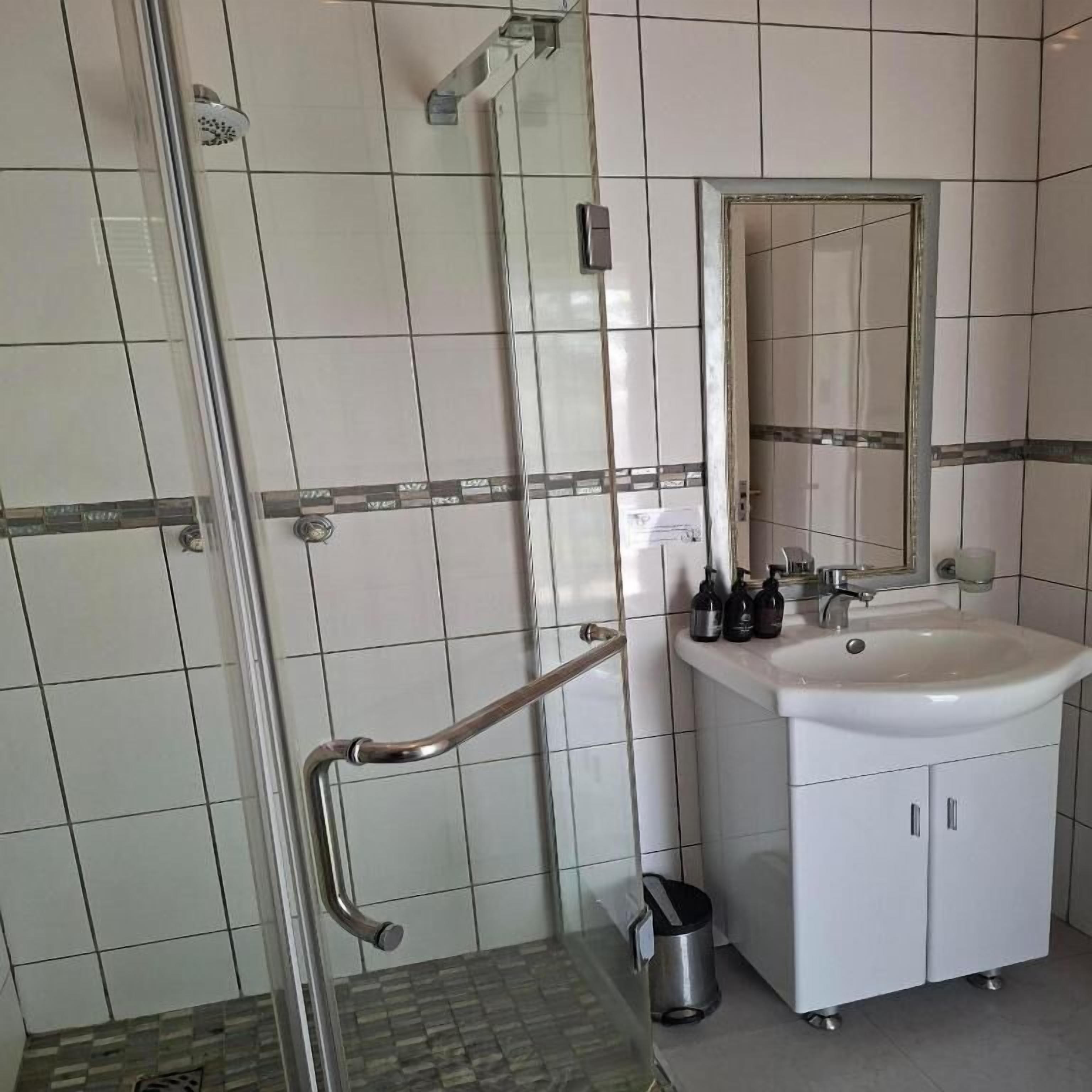 Een badkamer met een wit wastafelmeubel, spiegel en betegelde wanden.