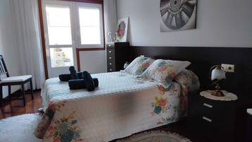 A bedroom with a bed, a nightstand, a lamp, and a window with curtains.