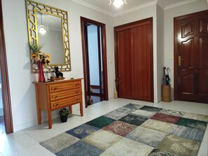 Un corridoio con un settimino in legno, uno specchio e un tappeto colorato.