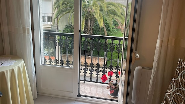 A room with a sliding glass door leading to a balcony with a metal railing and potted plants. - Xaquina Apartment (Melide)
