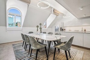 Eine moderne Küche mit weißen Schränken, einer Marmorarbeitsplatte und einem großen Fenster.