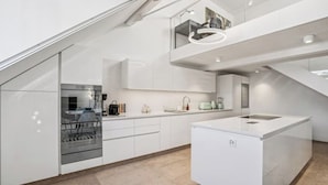 A modern kitchen with white cabinetry, a built-in oven, and a central island. - Old Town Penthouse | 360° Views | Rooftop Terrace (Zürich)