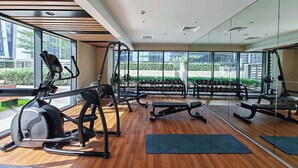 Ein modernes Fitnessstudio mit Cardiogeräten, Kurzhanteln und einer Spiegelwand.