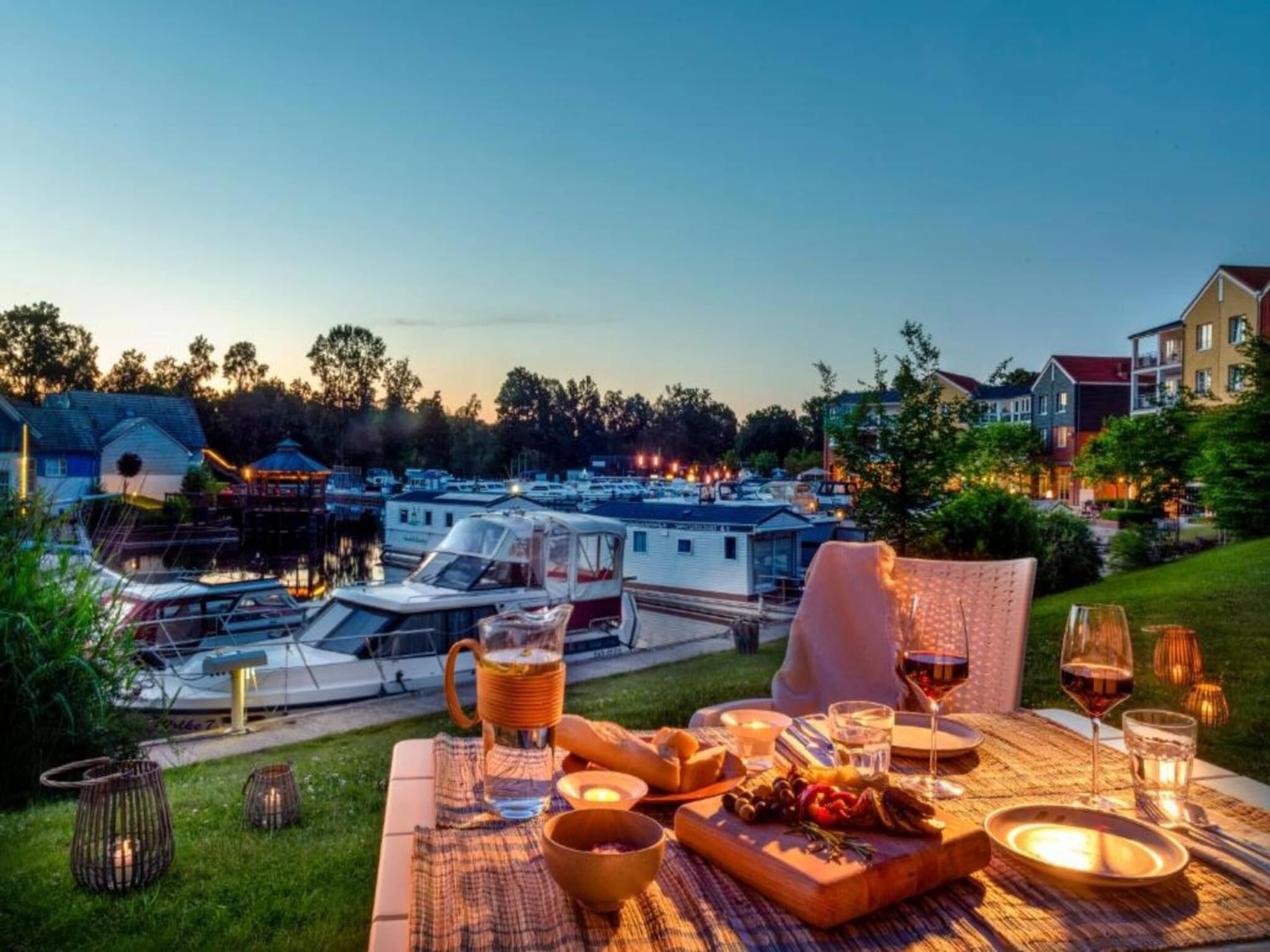 A dining table set outdoors with a view of boats and buildings in the background.