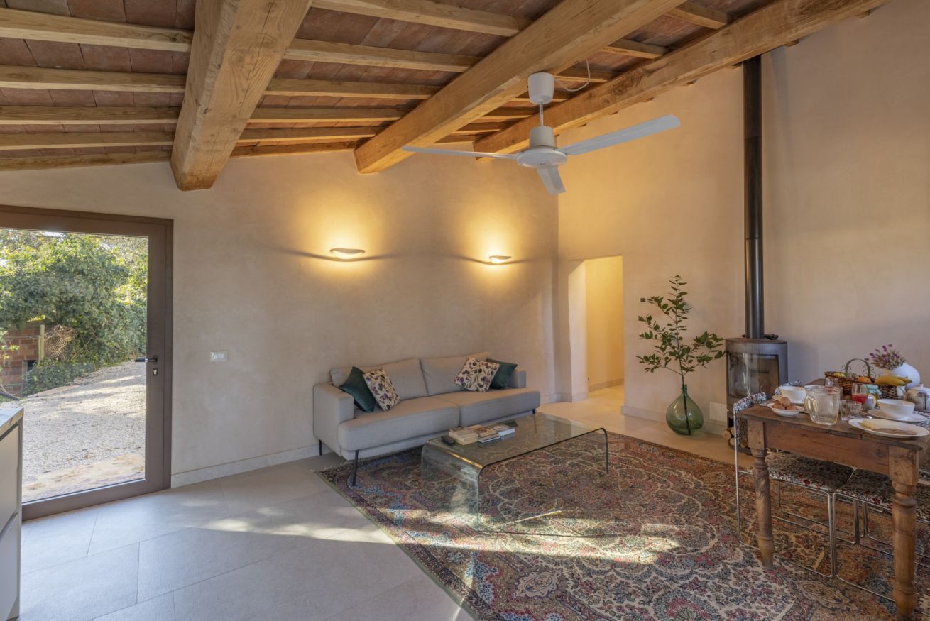 Een moderne woonkamer met een bank, een glazen salontafel, een kamerkleed met patroon, een houten plafond en een open haard.