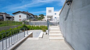 Un edificio moderno con una scala che conduce a una terrazza sul tetto, immerso nel verde e circondato da altri edifici residenziali.