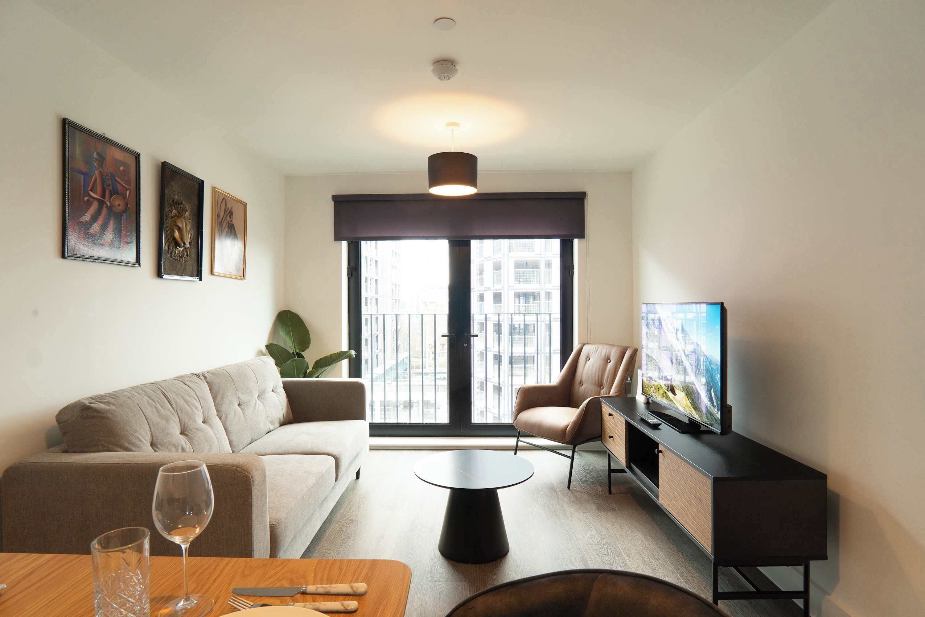 A modern living room with a sofa, a coffee table, a TV on a stand, and artwork on the wall.
