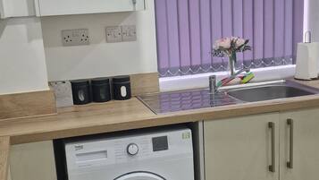 Una cocina compacta con lavadora, encimera de madera y armarios.