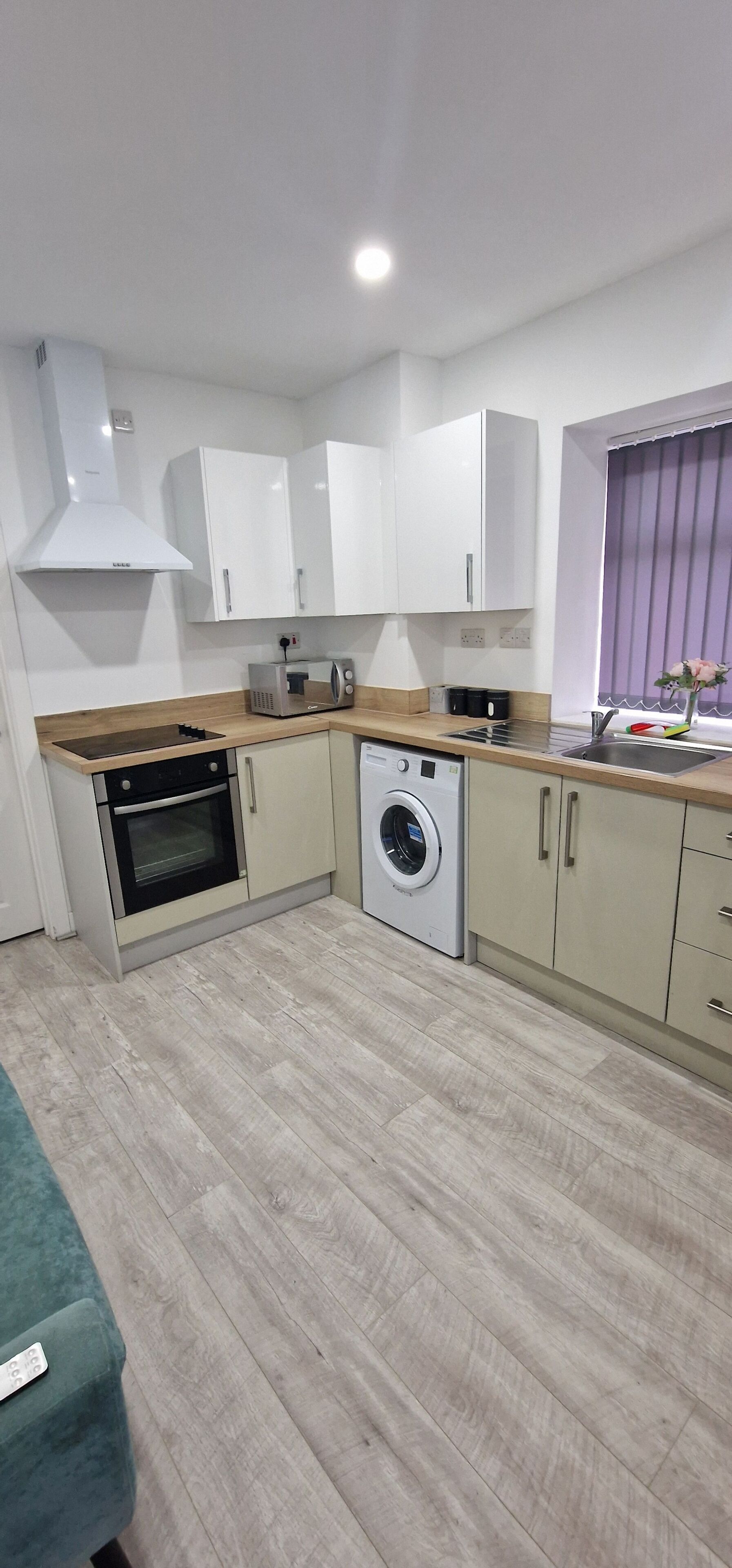 A compact kitchen with a microwave, oven, and washing machine.