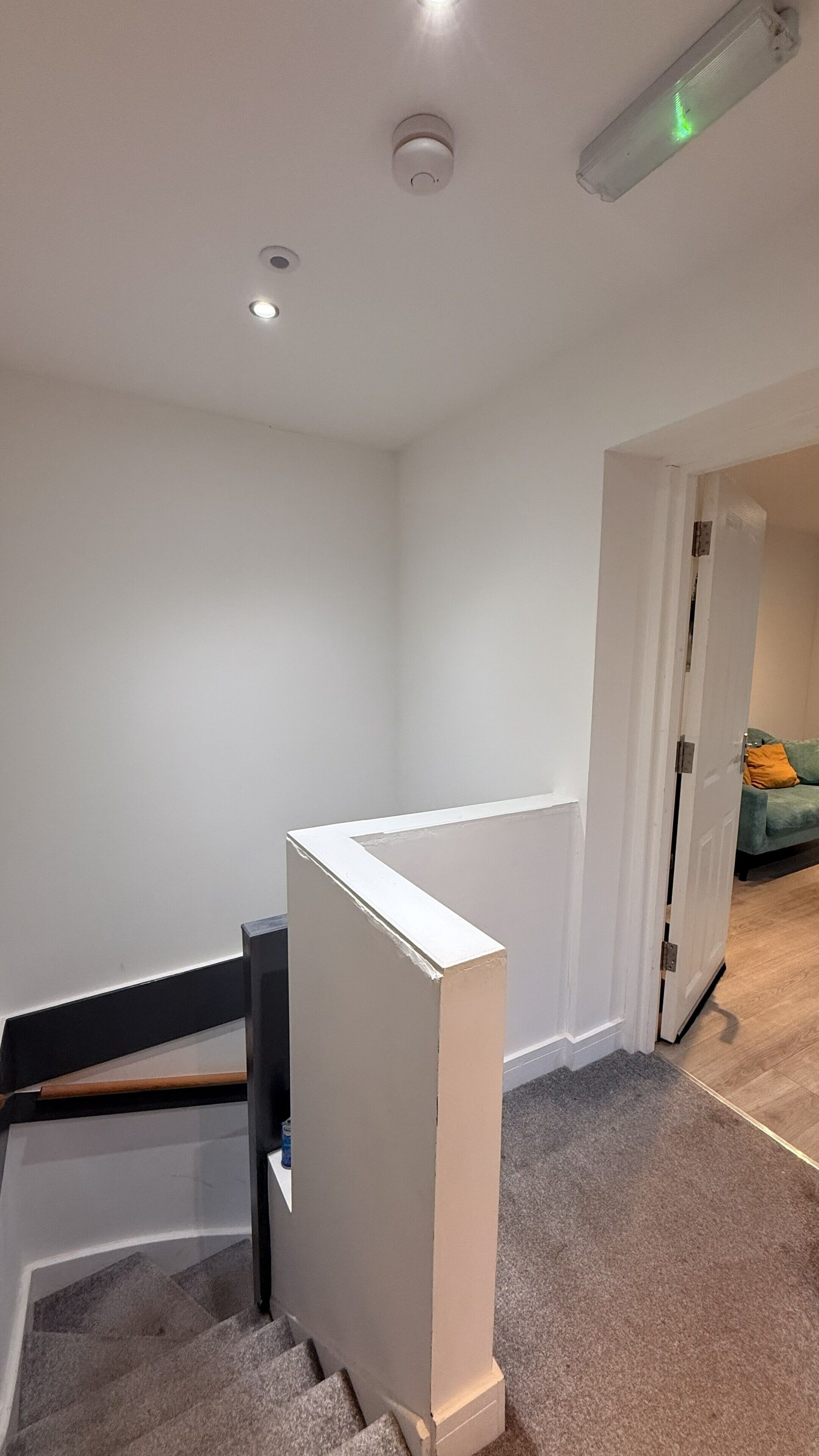 A staircase with a white handrail, carpeted steps, and a door leading to another room.