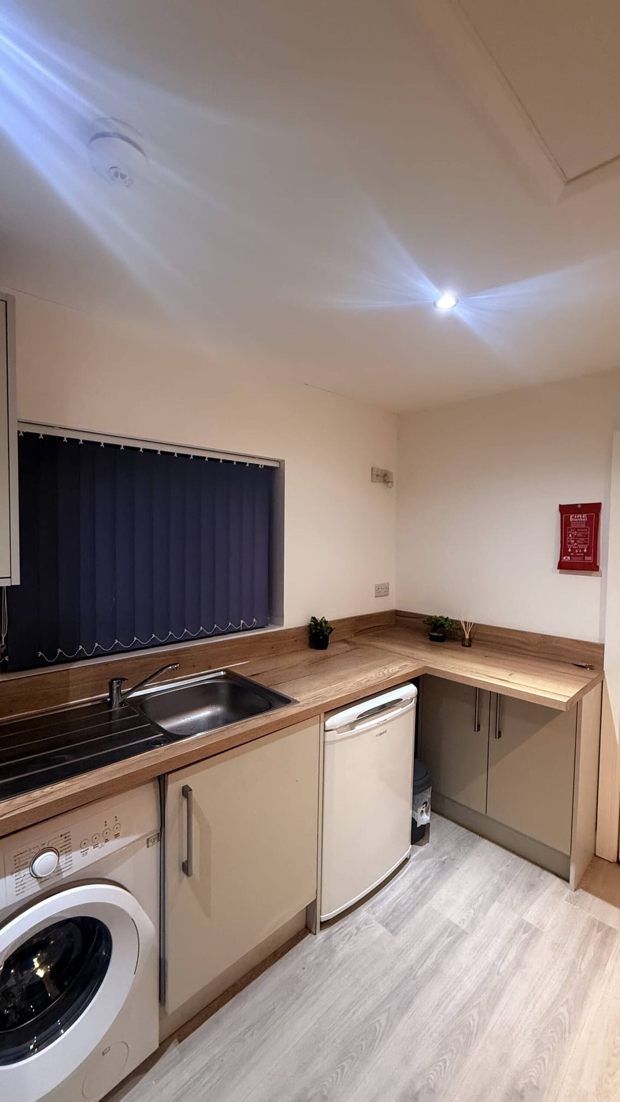 A compact kitchen with a washing machine, a sink, and a small refrigerator.