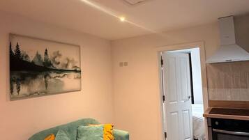 A modern living room with a teal sofa, a coffee table, and a painting on the wall.