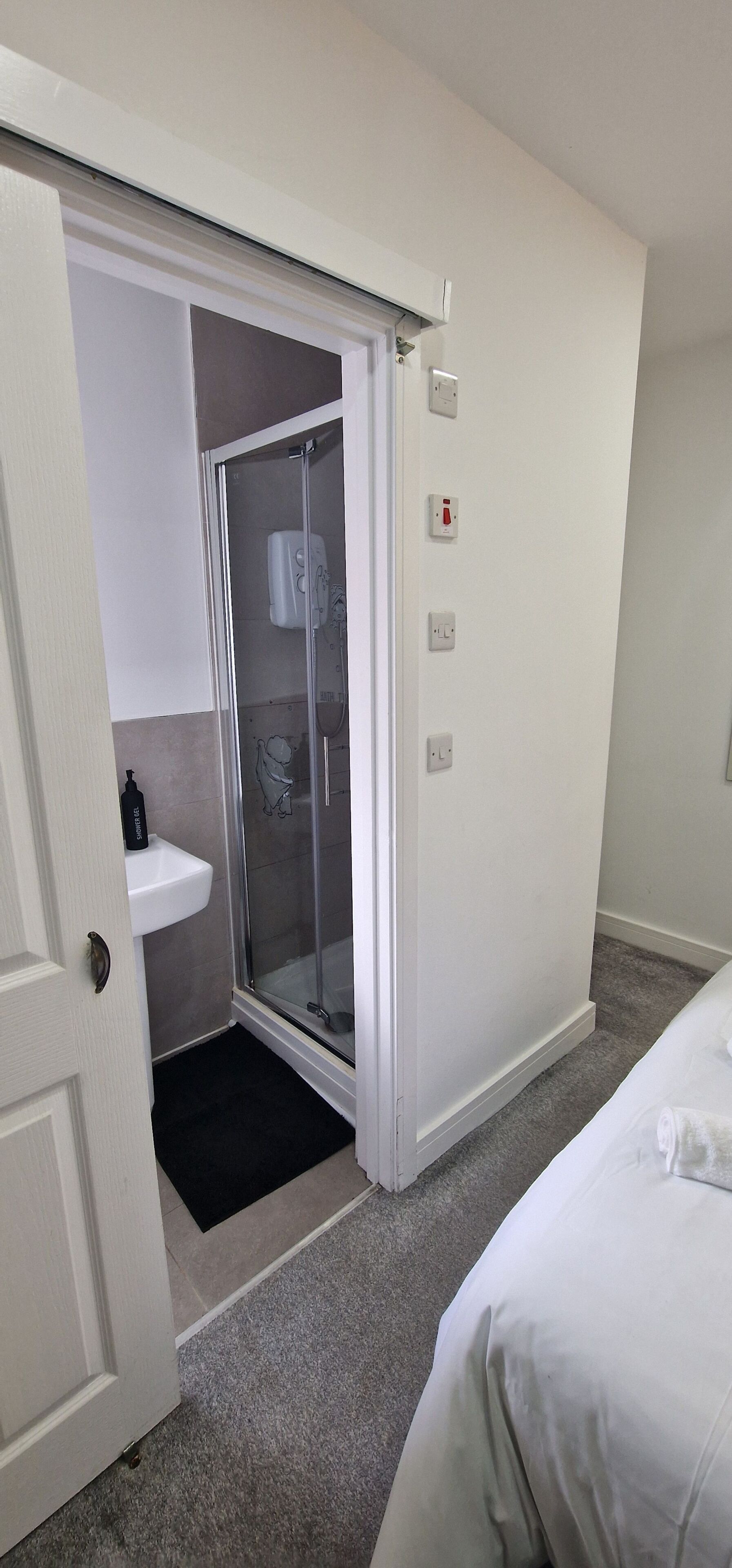 Een hotelkamer met een douche, wastafel en een bed.