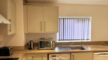 A compact kitchen with a washing machine, a toaster, and a sink.