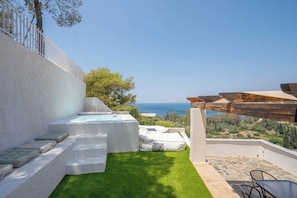 Eine Terrasse mit Meerblick, einem Whirlpool und einer Sitzecke.