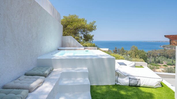 Un área de estar moderna al aire libre con piscina, escalones y vistas al mar.